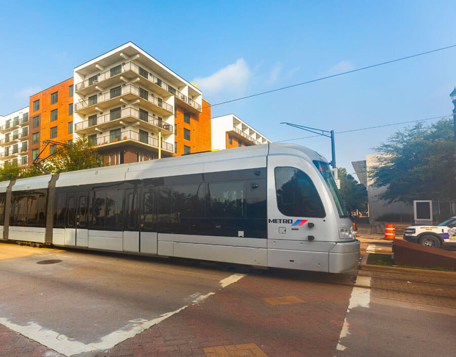 METRORail train moving along in the foreground with many apartment buildings in the background..