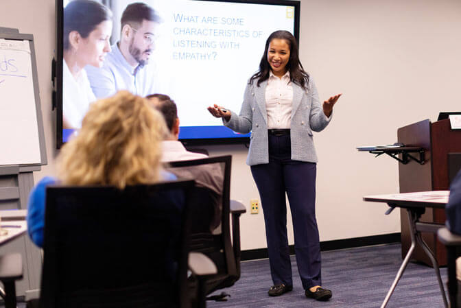 Instructor acknowledges main raising his hand with a question during a corporate training session.