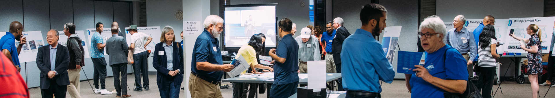 Community members interact with METRO in a large room filled with METRONext easel signs.