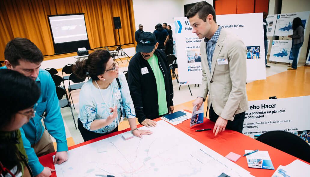 METRO representative interacting with community members next to a METRONext map on a table.