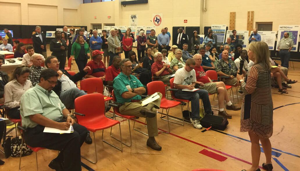 Community members seated for a presentation with METRONext easel signs in the background.