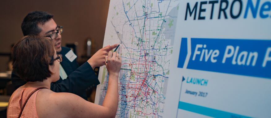 METRO representative showing something to a community member on a METRO transportation map at a METRONext community meeting