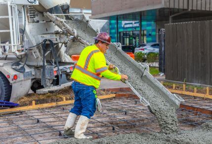 Construction worker helping to pour concrete on a sidewalk along the 56 Airline / Montrose route.
