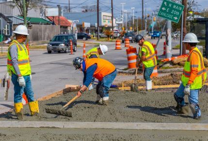 Construction workers digging up a sidewalk along the 56 Airline / Montrose route.