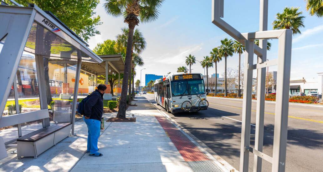 METRO rider standing at a bus stop waiting to board an 82 Westheimer bus.
