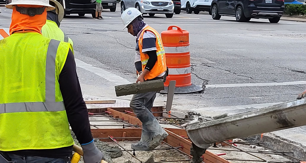 Construction workers smoothing out concrete.