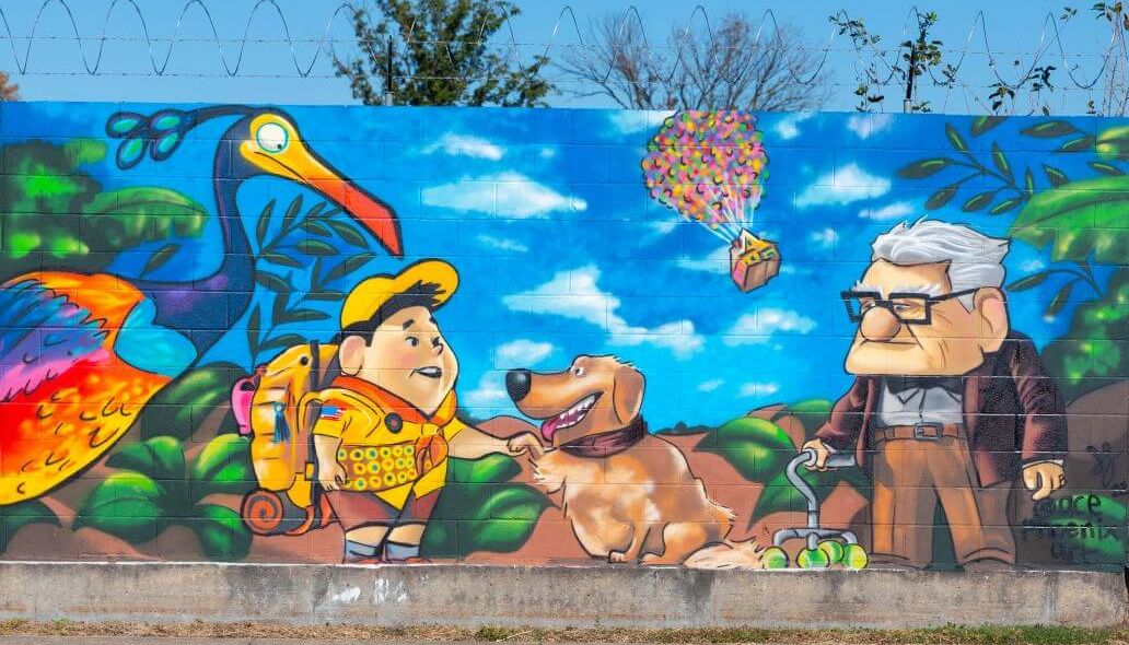 Mural of a colorful bird along with a young boy, a dog and a senior citizen along the outer wall of the Kashmere bus operating facility at 5700 Eastex Freeway in Houston