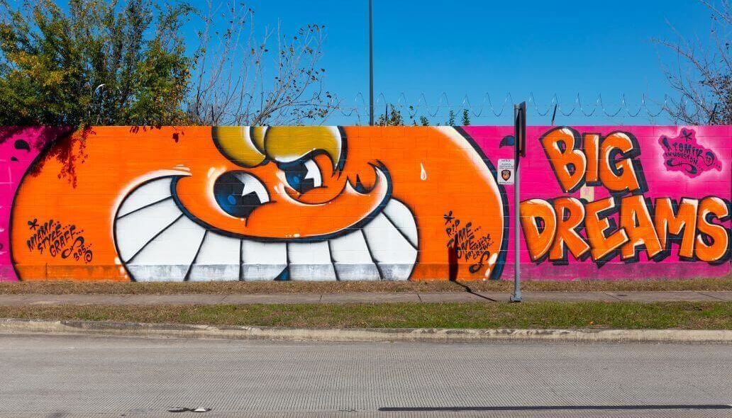 Mural of a smiling orange character next to the words "Big Dreams" along the outer wall of the Kashmere bus operating facility at 5700 Eastex Freeway in Houston