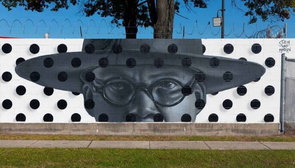 Mural of a man wearing glasses and wearing a hat along the outer wall of the Kashmere bus operating facility at 5700 Eastex Freeway in Houston