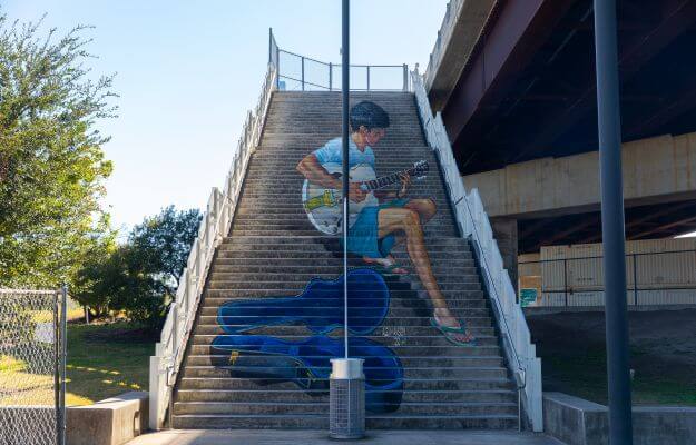 Mural of boy playing a guitar painted on the stairs at Burnett Transit Center - 1450 North Main St. in Houston.
