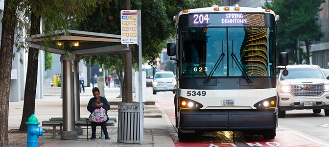 Passenger checks phone at bus stop as park and ride bus approaches