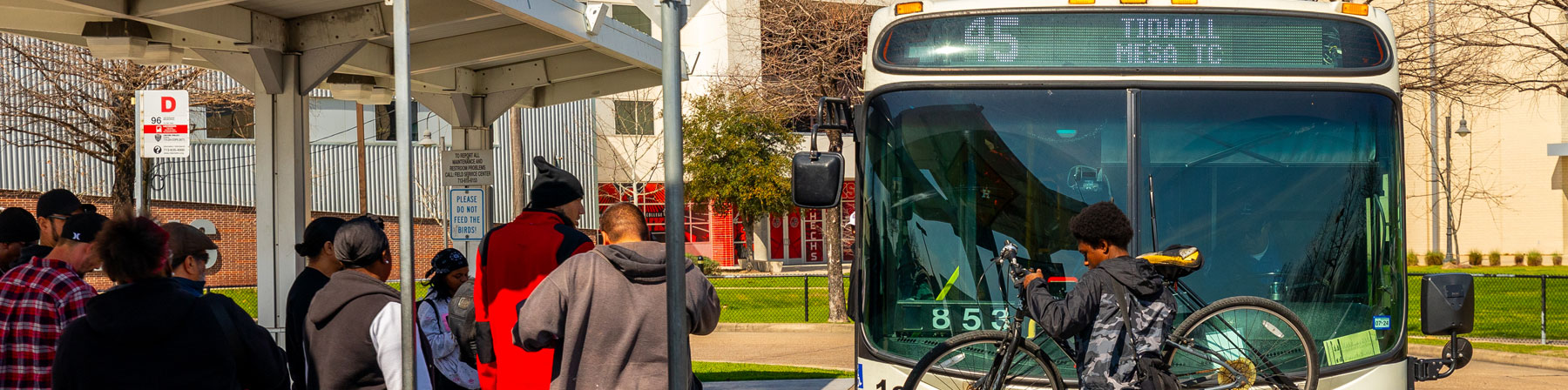 Customers boarding the 45 Tidwell local bus and a bike rider mounting bike on bike rack.