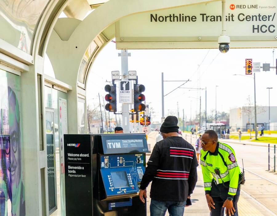 Rider on Rail platform with METRO Fare Inspector getting a rail ticket at a Ticket Vending Machine.