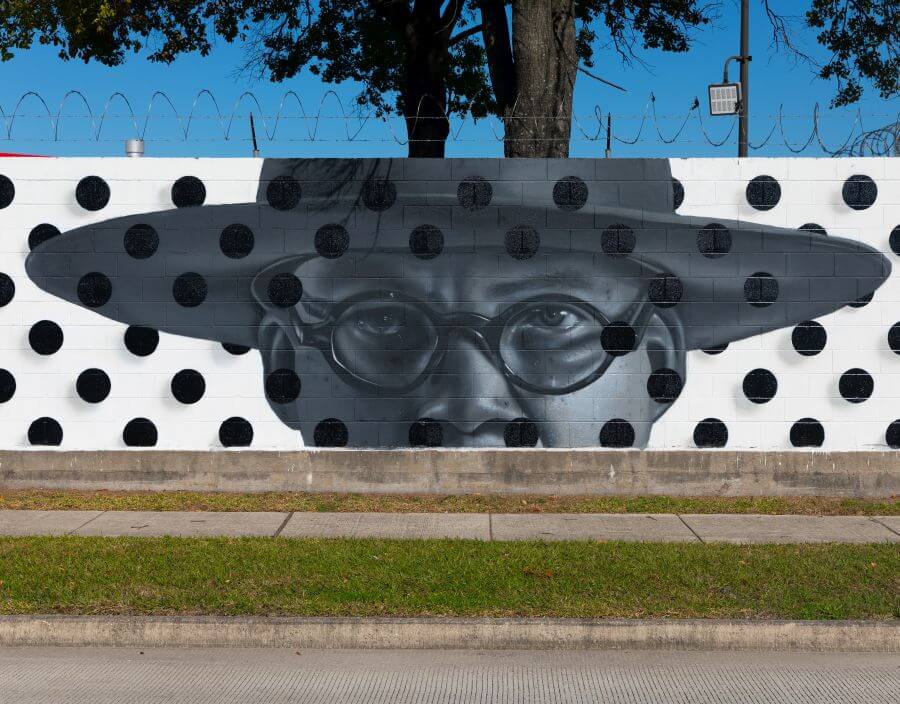 Mural of a man wearing glasses and wearing a hat along the outer wall of the Kashmere bus operating facility at 5700 Eastex Freeway in Houston