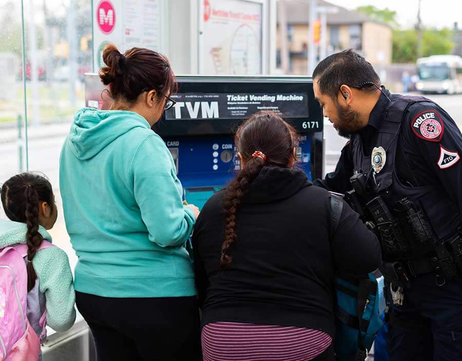 METRO Police officer assisting customers purchase rail fare items at Ticket Vending Machine.