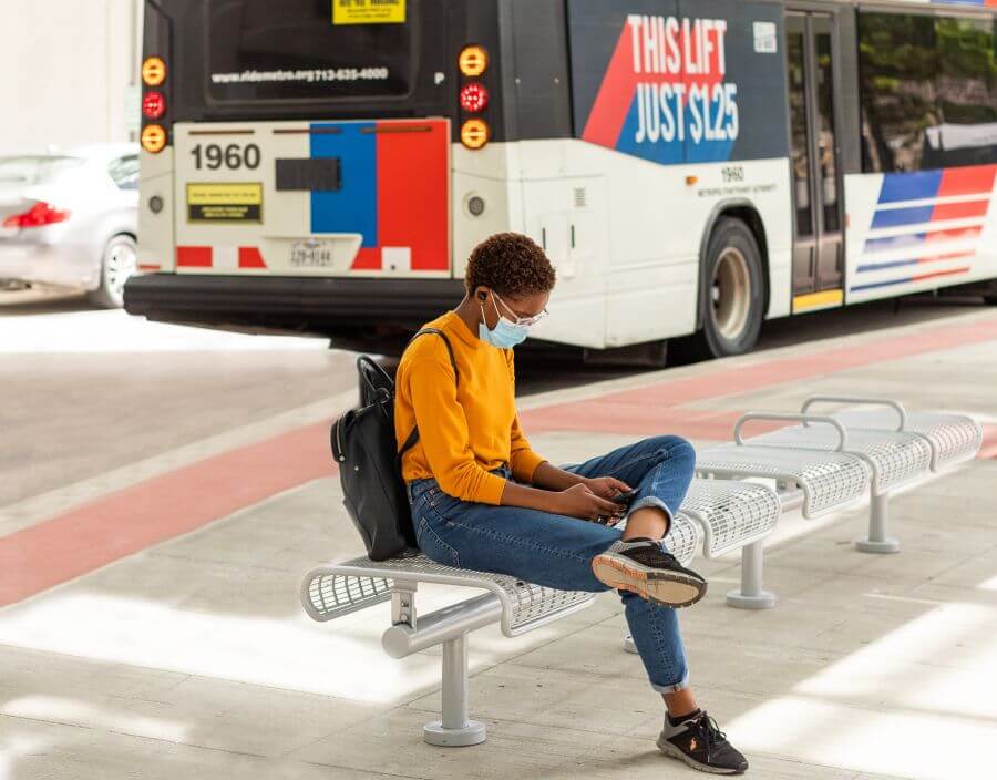 Customer seated and looking at her phone as METRO bus passes by in the background.