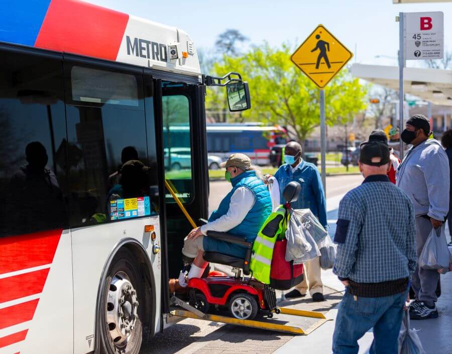 Customer boarding METRO bus using electric wheelchair.