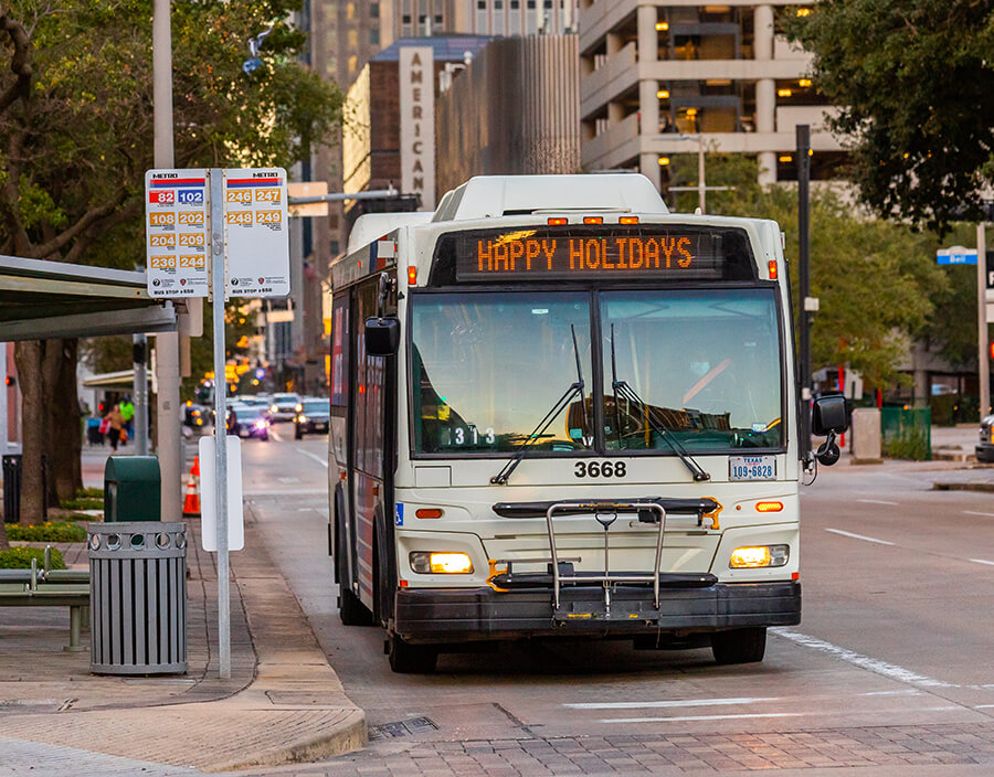 METRO local bus traveling in downtown Houston with a readerboard that says Happy Holidays.