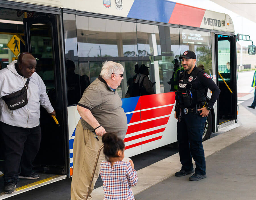 Riders getting off bus and greeted by METRO Police Officer.