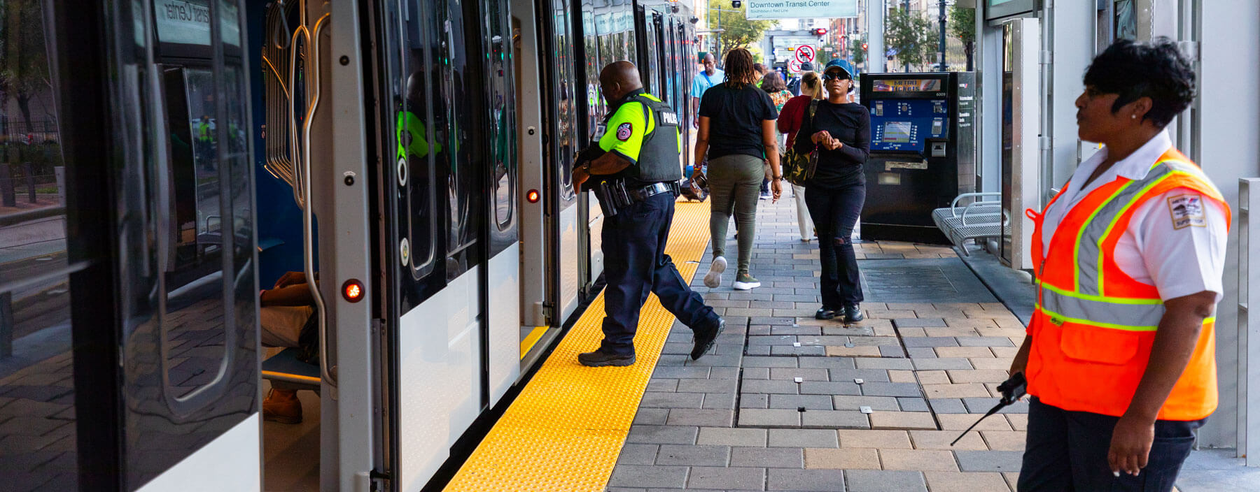 METRORail riders and METRO Police Officer boarding train while a METRO safety person stays on platform.