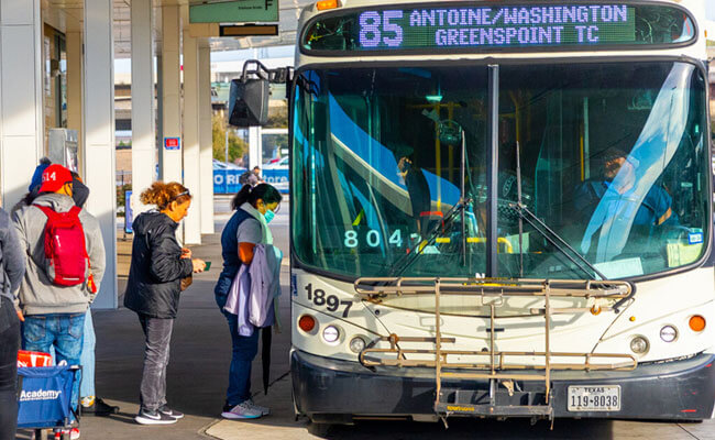 A line of riders boarding the METRO bus at a transit center.