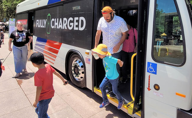 Earth Day event, family getting off electric bus.