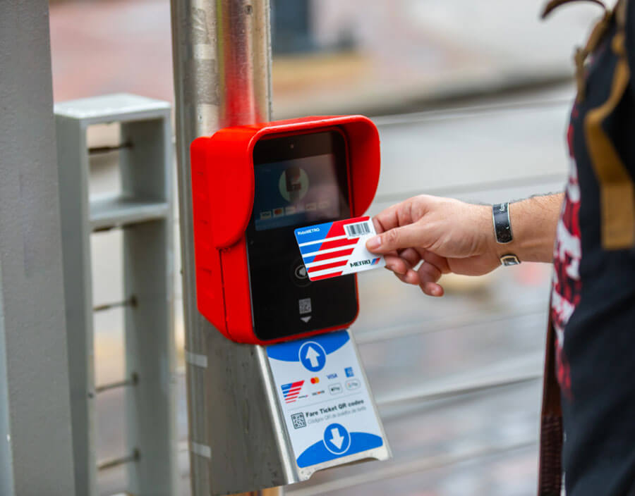 Customer tapping fare card validator on rail line.