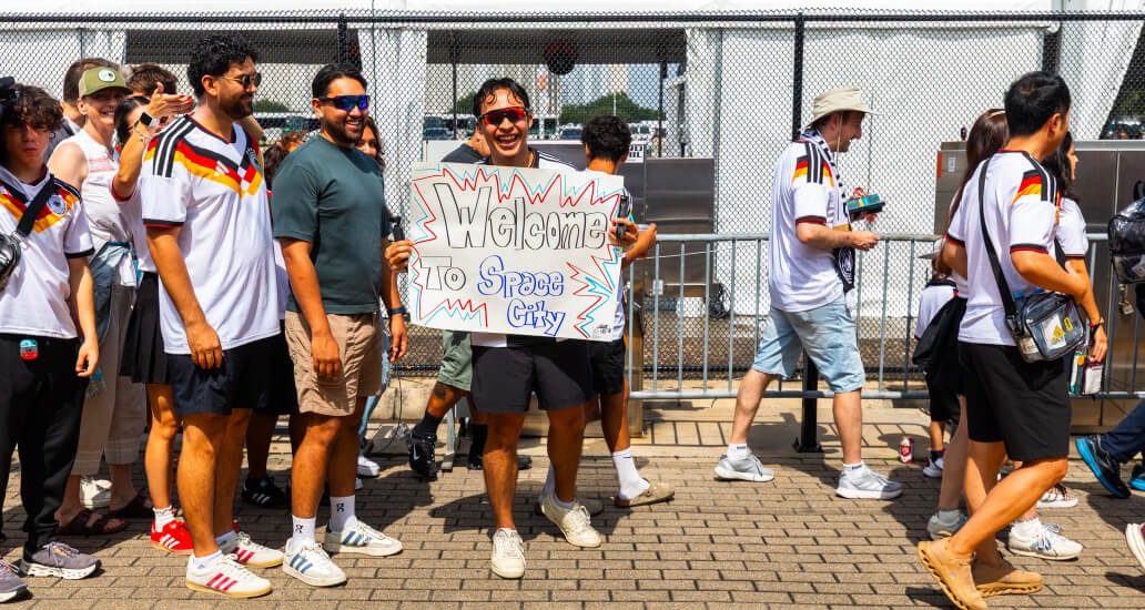 Man holding a sign that reads “Welcome to Space City” on a METRORail platform.