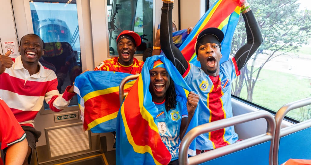 METRO riders wearing Congo DR soccer jerseys and smiling on the train.