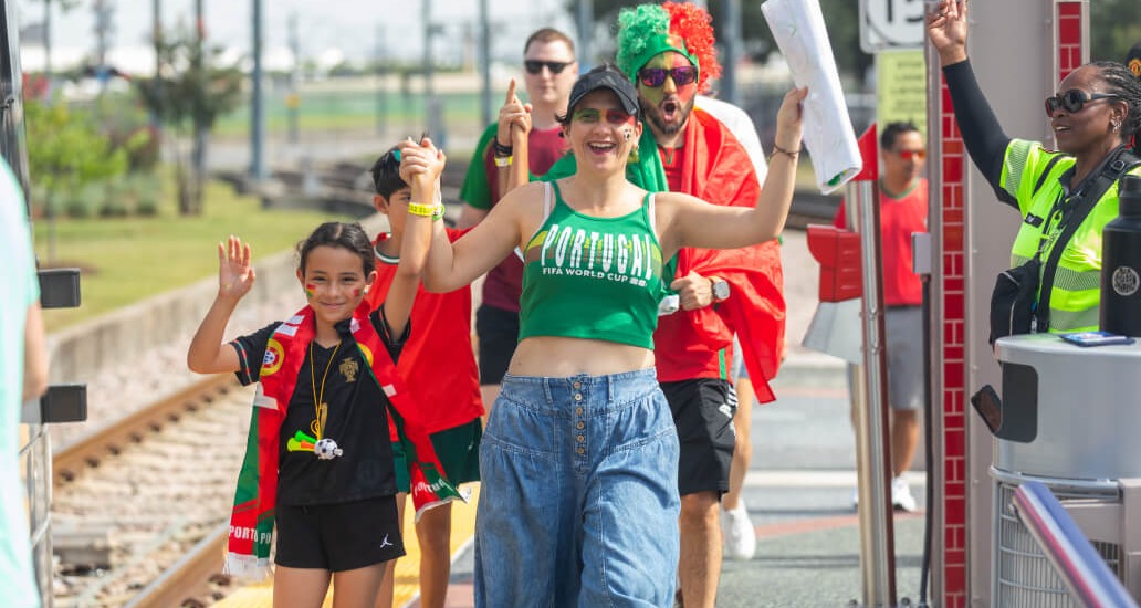 Riders wearing Portugal team colors walking on the METRORail platform at Fannin South Transit Center.