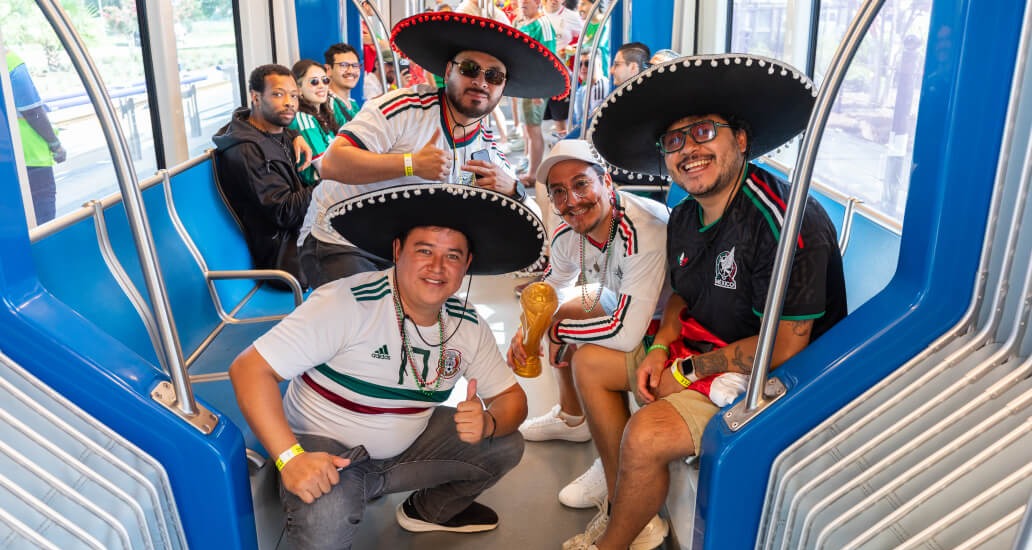 Four riders wearing Mexico team colors and sombreros onboard the train.