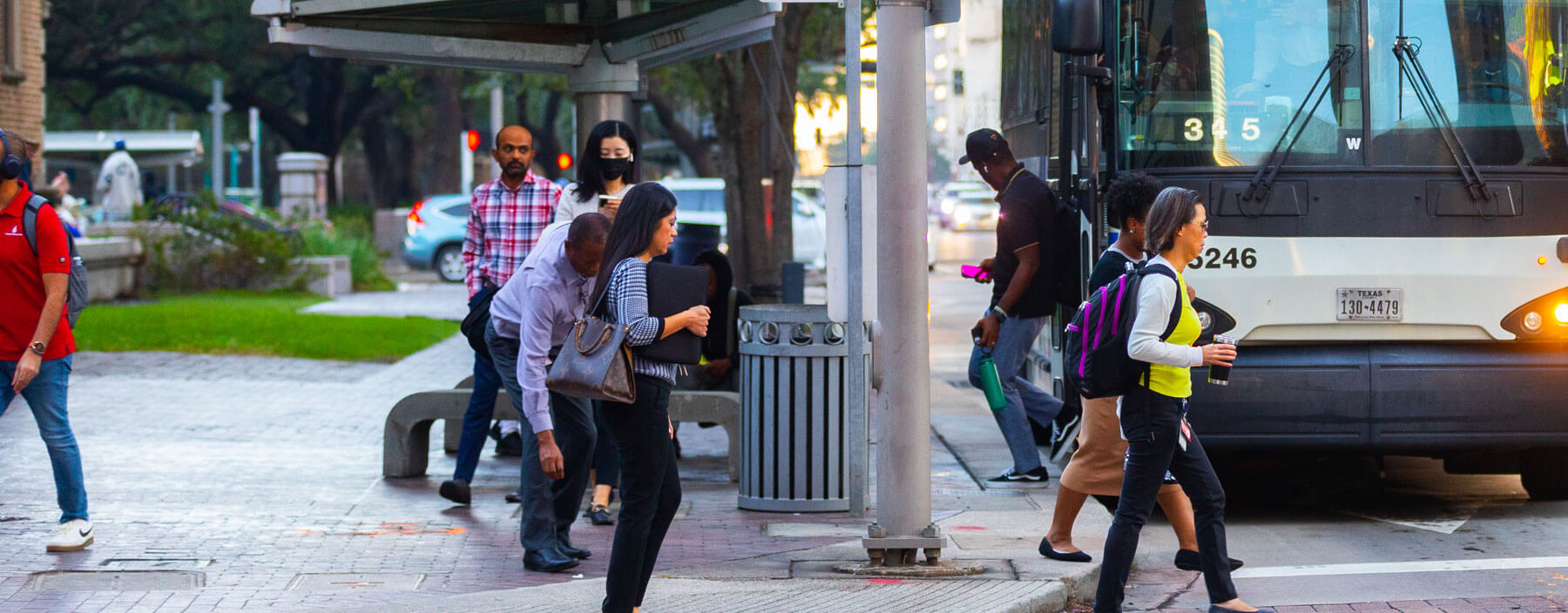 Riders waiting at bus shelter and other riders getting off bus in downtown.