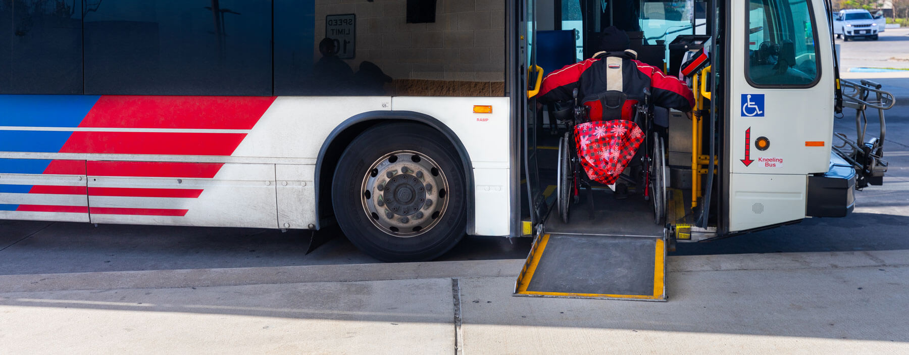 Rider in wheelchair using ramp to board a METRO local bus.