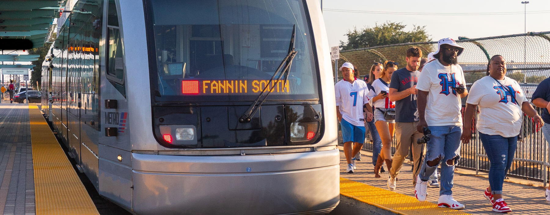 Riders getting off METRORail train and walking towards an event.