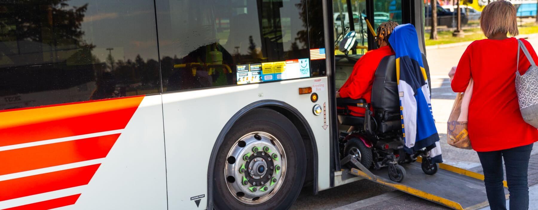 Rider on electric powered wheelchair boarding METRO local bus.