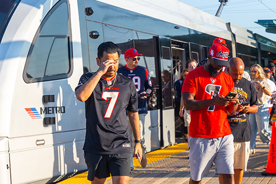 Texans fans walking out of train onto the rial platform towards NRG Stadium.