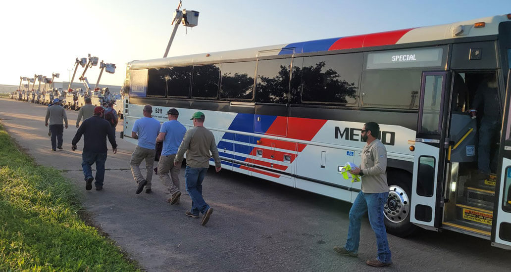 Crews getting of bus to get to utility trucks.