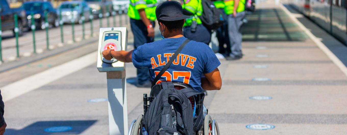 Man weating Astros Altuve shirt in wheelchair paying fare on rail platform