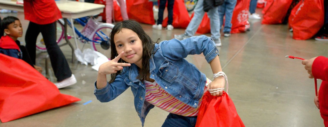 Happy child makes a peace sign at toy event for Barrios en el Navidad Toy Drive.