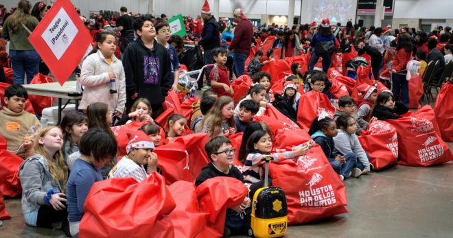 Yung recipients hold red bags filled with Christmas toys.