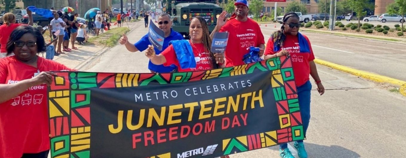 METRO employees  and Board Chair Sanjay Ramabhadran participate in a parade holding Juneteenth banner.