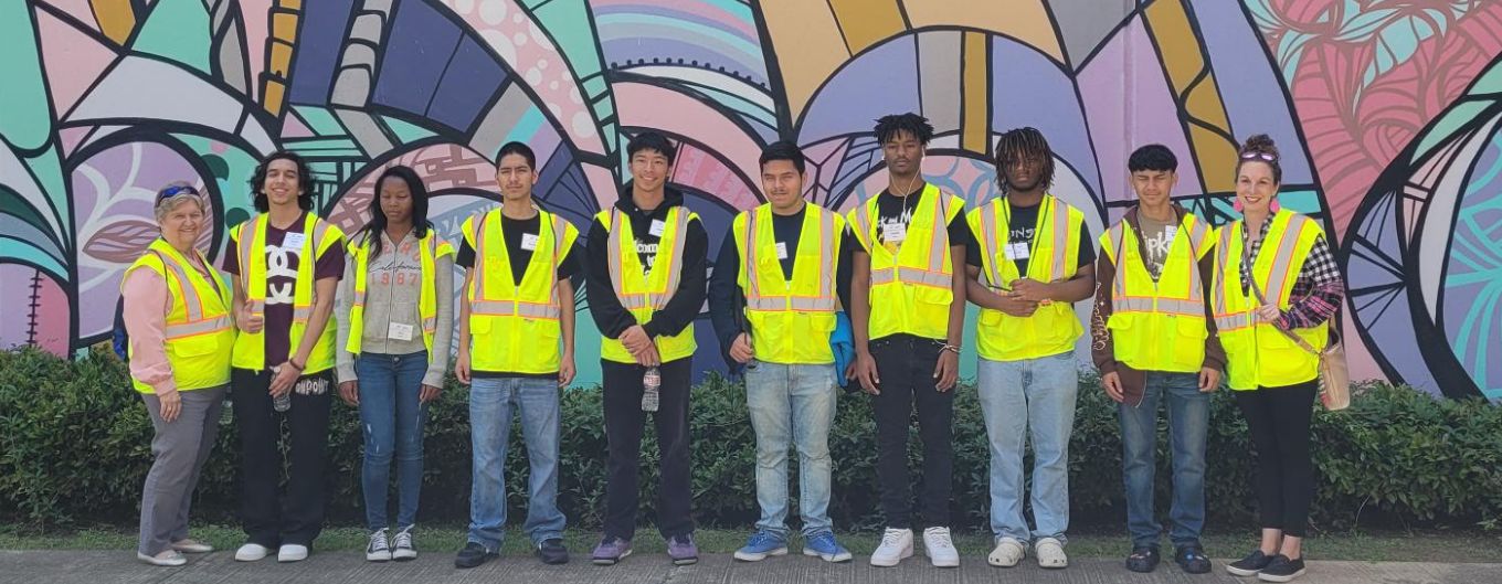 Students pose for a group photo in front of the ROC mural.