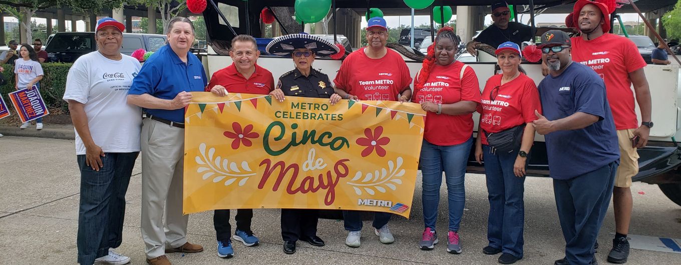 METRO staff hold a bright yellow banner in Houston's East End to celebrate Cinco de Mayo.