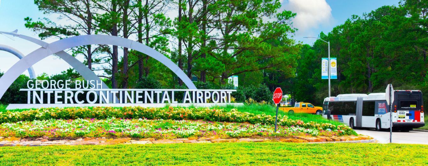 A METRO bus drives by the BISH IAH airport entrance sign.