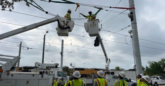 METRO workers service overhead catenary lines along rail.