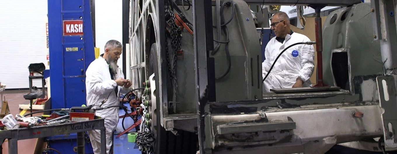 Two body shop mechanics fixing a METRO bus.