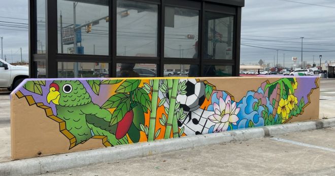 Mural in Gulfton featuring parrot, bamboo, lotus flower and jalepenos.
