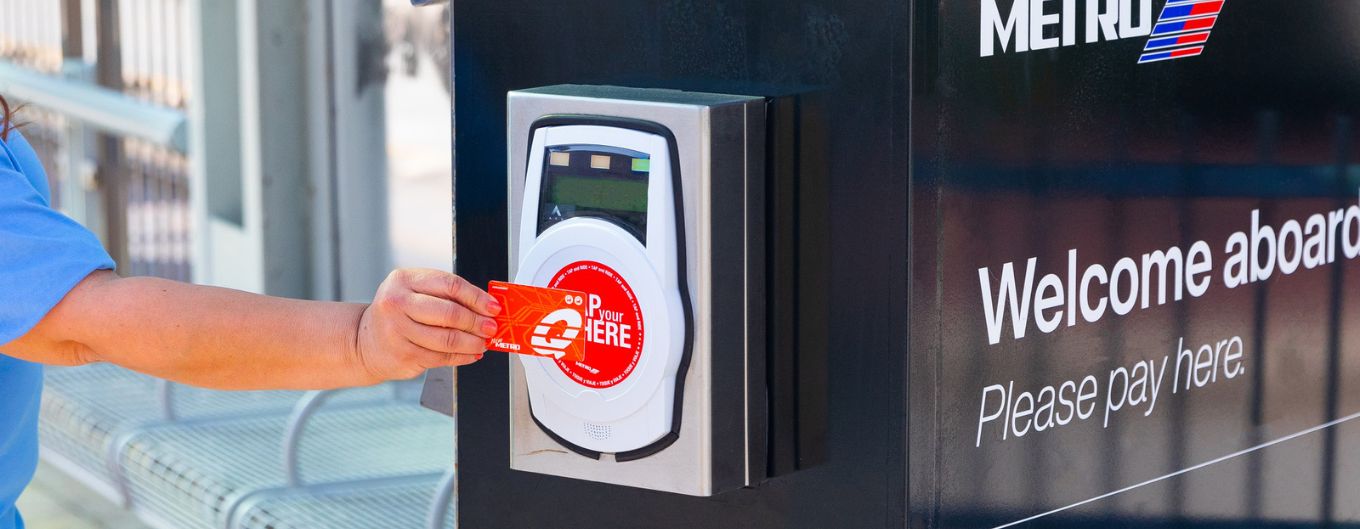 A woman's arm taps a METRO card at a fare payment station.