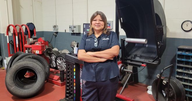 A female METRO employee tands in a tire shop.