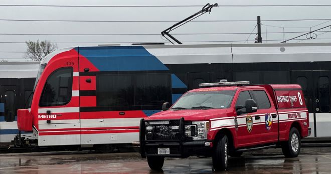 METRO light rail train with a HFD truck parked next to it.